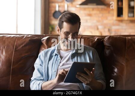 Happy millennial man using online app on tablet computer Stock Photo
