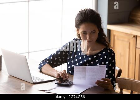 Focused young woman using calculating taxes, budget, costs, paying bill Stock Photo