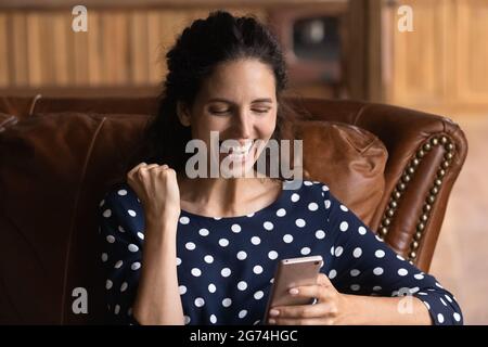 Overjoyed laughing cellphone user reading text screen Stock Photo