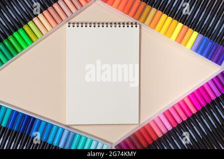 Colored felt-tip pens and a notebook on a beige background with a place for text top view. Bright banner for a stationery store. Stock Photo