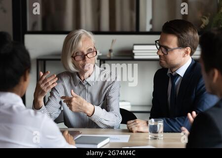 Middle aged mature mentor training interns, corporate coach teaching staff Stock Photo