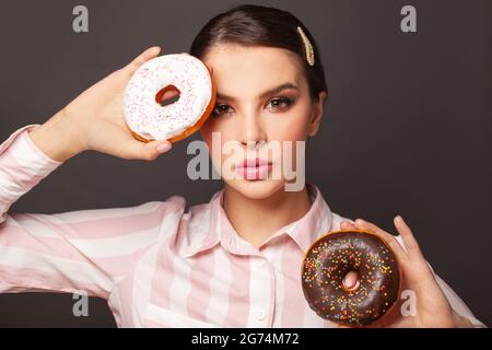 Hungry woman holding donuts on black background portrait, diet concept Stock Photo