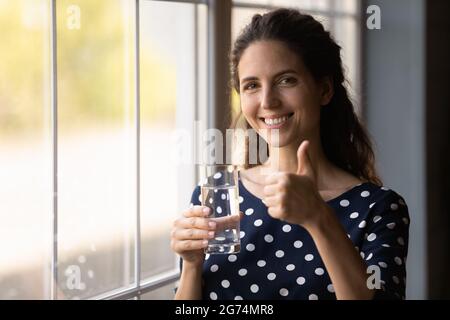 Happy Hispanic woman drinking fresh water, holding transparent glass Stock Photo