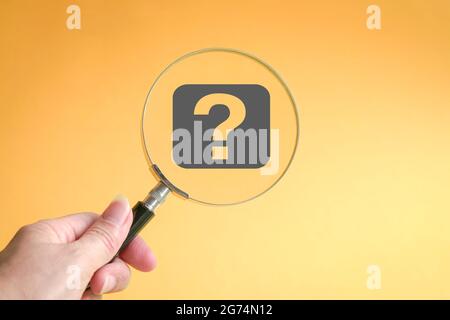 A large question mark through a magnifying glass. On yellow background. Stock Photo
