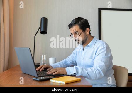 Man with a poor eyesight working inhis laptop, struggling to see Stock Photo
