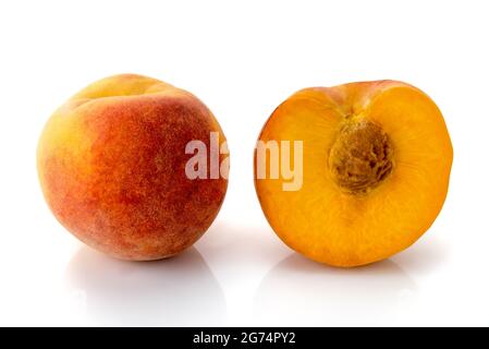 Italian Percoca peach variety with yellow flesh, one whole e altra in cross section, isolated on white, copy space Stock Photo