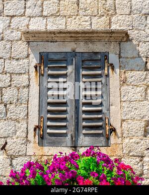 Old window with closed shutters decorated with flowers Stock Photo