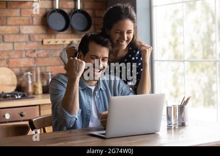 Happy excited young couple making winner yes gesture at laptop Stock Photo