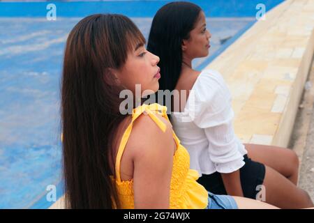 Two latina friends sitting in the park Stock Photo