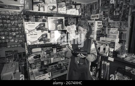 1980s historical a lady shopkeeper of a hardware store. Standing