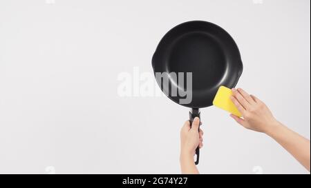 Cleaning Electric non stick pan. Hand on white background cleaning the non  stick pan with handy dish washing sponge which yellow color on the soft sid  Stock Photo - Alamy