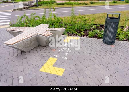 Parking space for bikes and electric scooters in the city. Signs painted on the pavement. Modern street bench, trash can Stock Photo