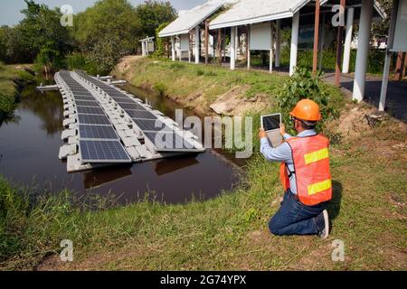 An Asian Engineers investigating floating solar panels Renewable Solar Power Plant. Stock Photo