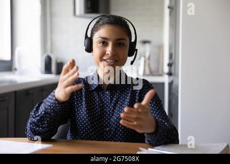 Happy funny Indian student wearing headphones looking at webcam Stock Photo