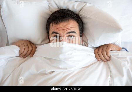 middle agem man in bed , hiding under the covers Stock Photo