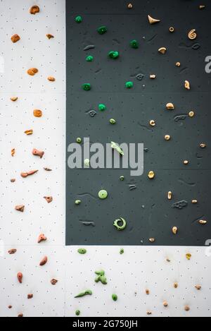 Artificial rock climbing wall showing various colored grips at outdoor gym adventure park. Stock Photo