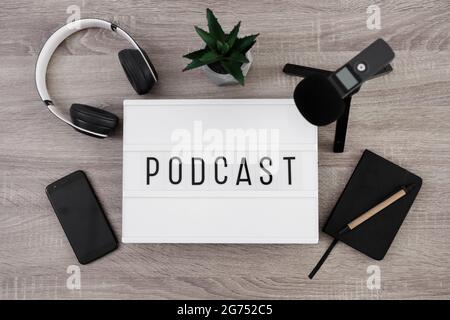 podcast concept - white lightbox with podcast word on the table with microphone, headphones, smartphone and notepad Stock Photo