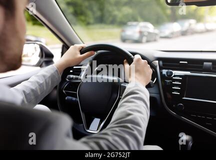 Personal transport, health care, man driving car, hand on steering wheel, looking at road ahead Stock Photo