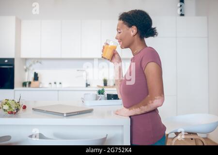 A dark-skinned woman drinking an orange juice Stock Photo