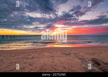 Port Noarlunga beach foreshore with people on the pier and dramatic sunset on the background Stock Photo