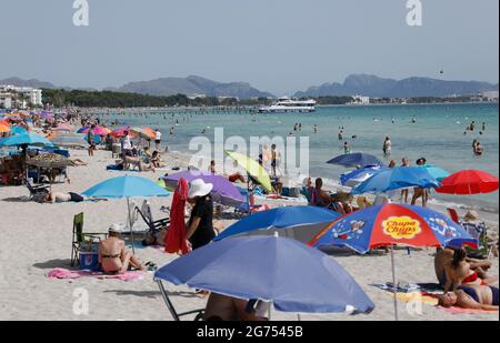 Maorca, Spain. 11th July, 2021. Under colorful umbrellas, many people enjoy the sun, sand and sea on the beach of Playa de Muro in the north of Mallorca. The federal government has declared all of Spain with Mallorca and the Canary Islands in view of rapidly increasing Corona numbers to the risk area. The practical effects for Mallorca holidaymakers are limited for the time being. Credit: Clara Margais/dpa/Alamy Live News Stock Photo