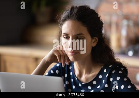 Focused adult student woman using laptop in kitchen Stock Photo