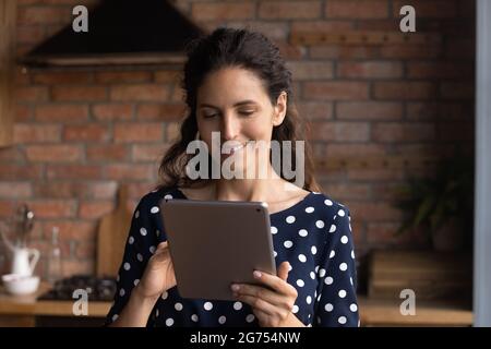 Happy Hispanic woman using computer tablet at home Stock Photo
