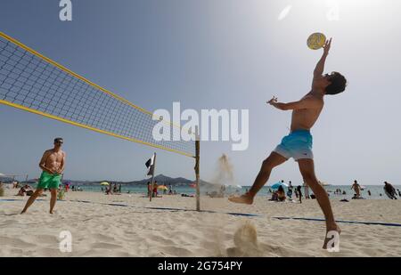 Spain. 11th July, 2021. Tourists Olli (r) and Birger from Rostock play volleyball on the beach of Playa de Muro in the north of Mallorca. The federal government has declared the whole of Spain with Mallorca and the Canary Islands in view of rapidly increasing Corona numbers as a risk area. The practical effects for Mallorca holidaymakers are limited for the time being. Credit: Clara Margais/dpa/Alamy Live News Stock Photo