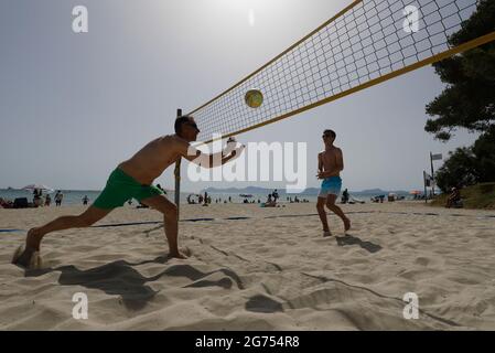 Spain. 11th July, 2021. The tourists Birger (l) and Olli from Rostock play volleyball on the beach of Playa de Muro in the north of Mallorca. The federal government has declared all of Spain with Mallorca and the Canary Islands in view of rapidly increasing Corona numbers to the risk area. The practical effects for Mallorca holidaymakers are limited for the time being. Credit: Clara Margais/dpa/Alamy Live News Stock Photo