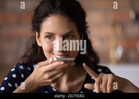 Happy Latin woman with cellphone recording audio message Stock Photo