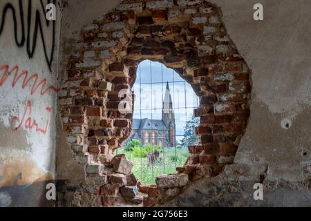 Manheim, NRW, Germany, 07 05 2021, church in Manheim, a village that is being demolished for open-cast lignite mining, view through a hole in a brick Stock Photo