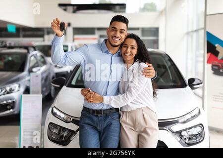 Happy young family buying new car in luxury showroom Stock Photo