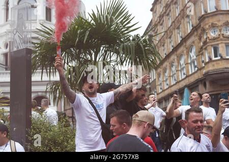London, UK. 11th July, 2021. England fan with a flare at Leicester Square ahead of the Euro 2020 Final. Credit: Thomas Eddy/Alamy Live News Stock Photo