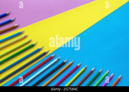 Colorful colored pencils on multicolored paper background. Free space for text Stock Photo