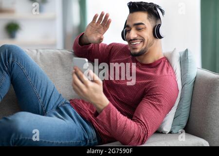 Cheerful arab guy having video chat, using mobile phone Stock Photo