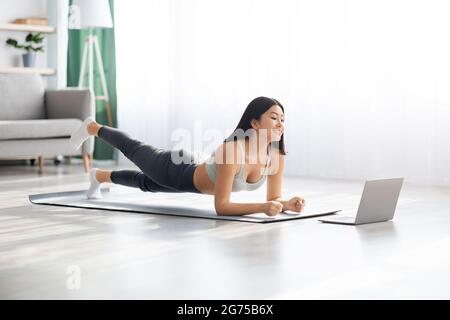 Sporty Asian Female Training In Front Of Laptop At Home Stock Photo