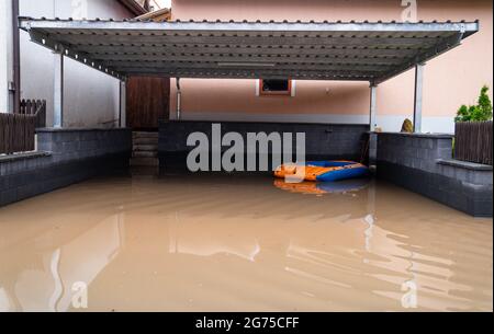 Willersdorf, Germany. 11th July, 2021. An inflatable boat floats in a flooded carport. Parts of Franconia are still under water due to yesterday's high water. Credit: Nicolas Armer/dpa/Alamy Live News Stock Photo