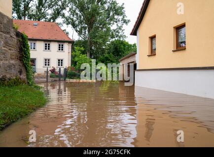 Willersdorf, Germany. 11th July, 2021. The Aisch river has overflowed its banks and flooded parts of the village of Willersdorf. Parts of Franconia are still under water due to yesterday's high water. Credit: Nicolas Armer/dpa/Alamy Live News Stock Photo