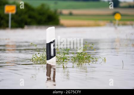 Willersdorf, Germany. 11th July, 2021. The Aisch, which has overflowed its banks, has flooded a country road. Parts of Franconia are still under water due to yesterday's high water. Credit: Nicolas Armer/dpa/Alamy Live News Stock Photo