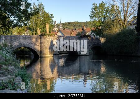 View to the old Grünbach bridge in Gerlachsheim with baroque monastery church in the background. Stock Photo