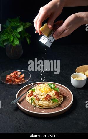 Traditional Italian Pasta Carbonara with bacon, cheese and egg yolk. Spaghetti Sprinkled Cheese on Plate on Dark Background. Stock Photo