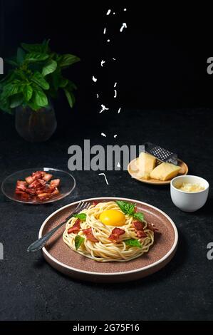 Traditional Italian Pasta Carbonara with bacon, cheese and egg yolk. Spaghetti Sprinkled Cheese on Plate on Dark Background. Stock Photo