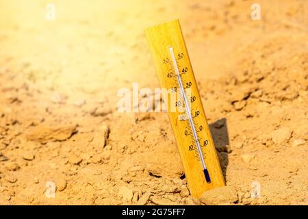 Thermometer shows very hot summer temperature in dry desert sand dunes. Climate change/global warming/desert concept. Stock Photo