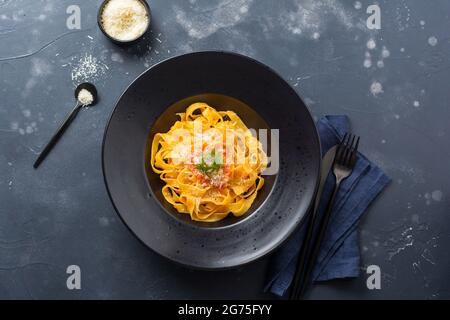 Fettuccine pasta with traditional Italian passat sauce and parmesan cheese in light plate on old white concrete background. Top view. Stock Photo