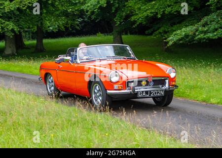 A front view of orange 1974 70s MG B (MGB) orange 2dr 1798cc roadster; vintage classic sports car retro British driver vehicle automobile, UK Stock Photo