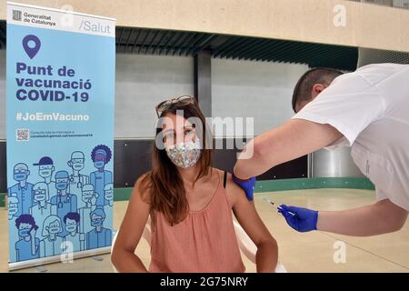 Calafell, Spain. 11th July, 2021. A nurse administers the first dose of Comirnaty (PfizerBioNTech) COVID-19 mRNA Vaccine to a young woman at the Calafell Vaccination Center. The Department of Health of Catalonia through the Xarxa Santa Tecla de Tarragona in prevention against the contagion of SARS-CoV-2 Covid-19 has administered the first dose of the COMIRNATY vaccine (COVID-19 mRNA vaccine, Pfizer-BioNTech) to people between the ages of 16 and 34 at the vaccination center located at the Joan Ortoll Sports Pavilion in Calafell. Credit: SOPA Images Limited/Alamy Live News Stock Photo
