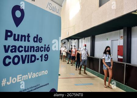 Calafell, Spain. 11th July, 2021. People between the ages of 16 and 34 are seen in a queue waiting to be vaccinated against Covid-19 at the entrance of the Calafell Vaccination Center. The Department of Health of Catalonia through the Xarxa Santa Tecla de Tarragona in prevention against the contagion of SARS-CoV-2 Covid-19 has administered the first dose of the COMIRNATY vaccine (COVID-19 mRNA vaccine, Pfizer-BioNTech) to people between the ages of 16 and 34 at the vaccination center located at the Joan Ortoll Sports Pavilion in Calafell. Credit: SOPA Images Limited/Alamy Live News Stock Photo