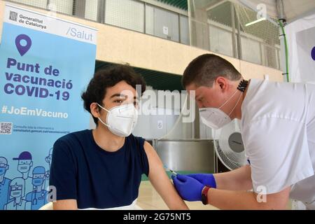 Calafell, Spain. 11th July, 2021. A health worker administers the first dose Comirnaty (PfizerBioNTech) COVID-19 mRNA Vaccine to young man at the Calafell Vaccination Center. The Department of Health of Catalonia through the Xarxa Santa Tecla de Tarragona in prevention against the contagion of SARS-CoV-2 Covid-19 has administered the first dose of the COMIRNATY vaccine (COVID-19 mRNA vaccine, Pfizer-BioNTech) to people between the ages of 16 and 34 at the vaccination center located at the Joan Ortoll Sports Pavilion in Calafell. Credit: SOPA Images Limited/Alamy Live News Stock Photo