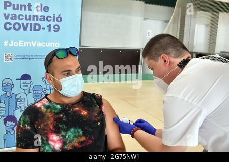 Calafell, Spain. 11th July, 2021. A health worker administers the first dose Comirnaty (PfizerBioNTech) COVID-19 mRNA Vaccine to a man at the Calafell Vaccination Center. The Department of Health of Catalonia through the Xarxa Santa Tecla de Tarragona in prevention against the contagion of SARS-CoV-2 Covid-19 has administered the first dose of the COMIRNATY vaccine (COVID-19 mRNA vaccine, Pfizer-BioNTech) to people between the ages of 16 and 34 at the vaccination center located at the Joan Ortoll Sports Pavilion in Calafell. Credit: SOPA Images Limited/Alamy Live News Stock Photo