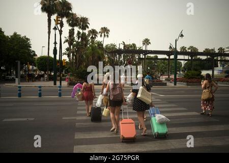 Malaga, Spain. 11th July, 2021. Tourists are seen carrying suitcases along a zebra crossing during a hot summer day.Spain live its first heat wave with high temperatures near 45º degrees in many cities of the country, according to the Spanish Meteorological Agency. Spaniards take advantage of beaches to cool off at the Mediterranean Sea and enjoy good weather. (Photo by Jesus Merida/SOPA Images/Sipa USA) Credit: Sipa USA/Alamy Live News Stock Photo